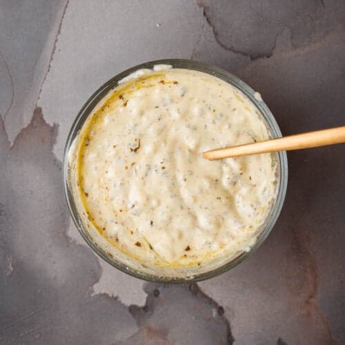 A bowl of pesto aioli with a wooden spoon.