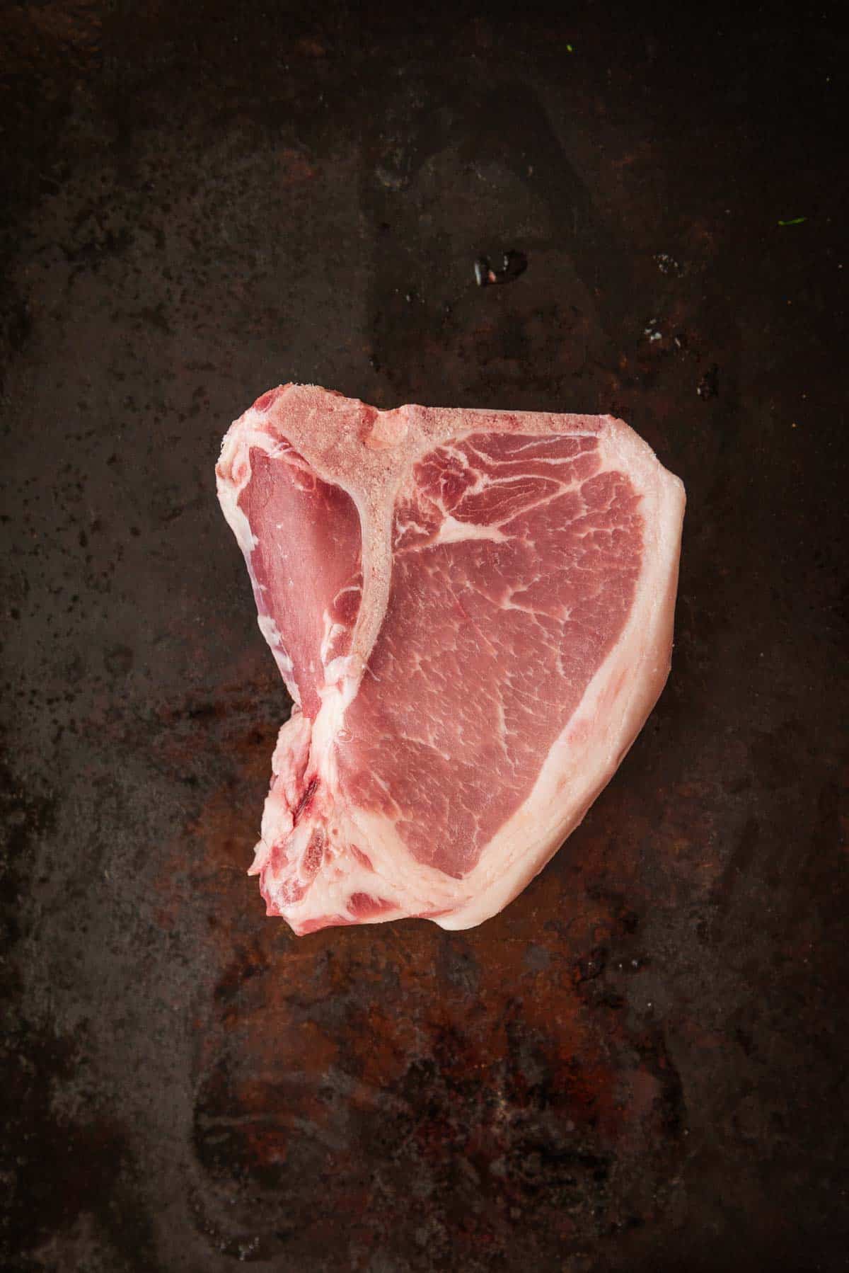 A piece of meat is sitting on a black surface.