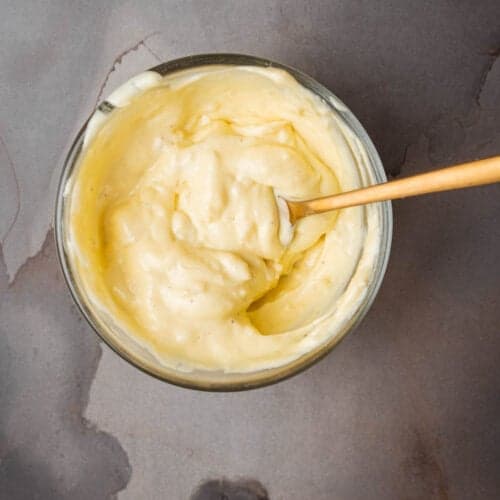 A bowl of roasted garlic aioli with a wooden spoon.