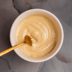 A bowl of rosemary truffle aioli with a spoon in it.