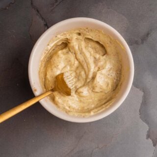 A bowl of umami garlic aioli with a spoon.