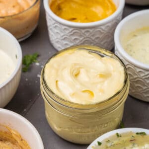 A variety of dips in bowls on a table.