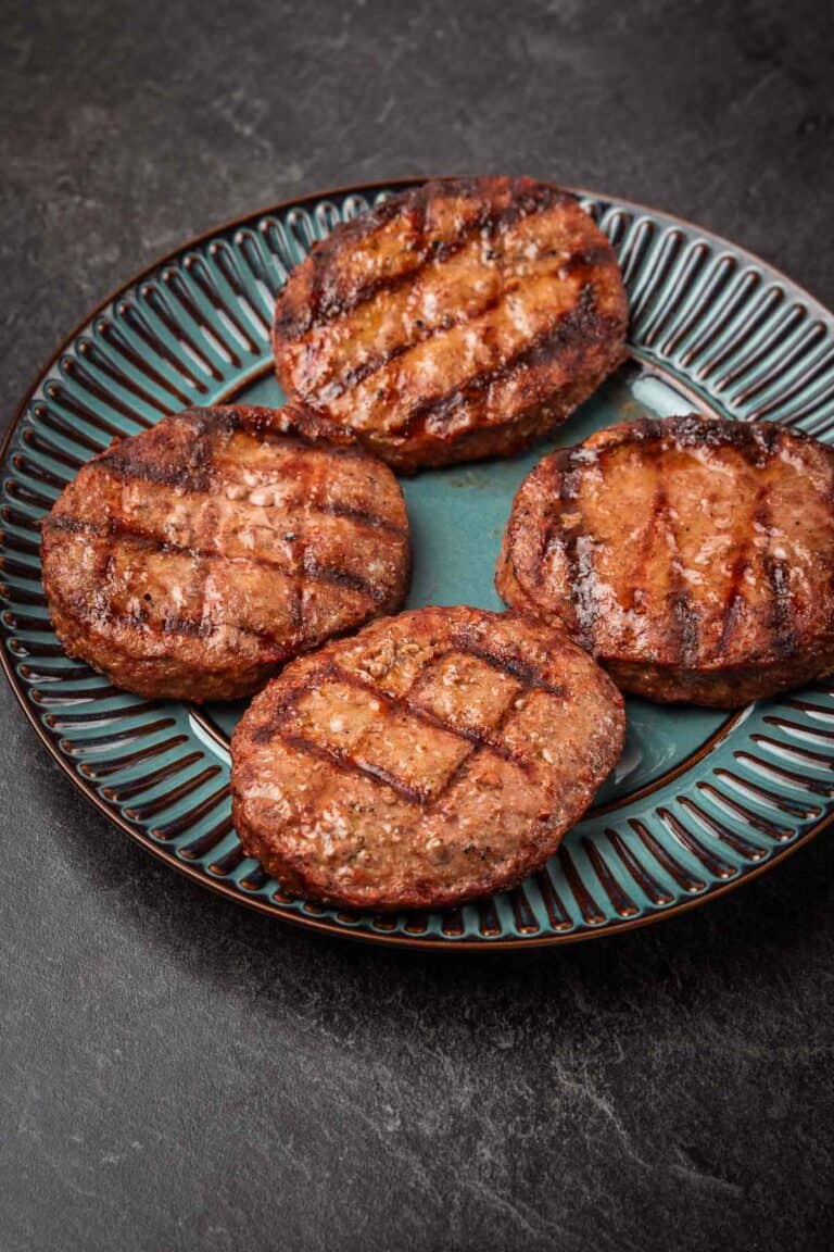 Four grilled burgers on a blue plate.