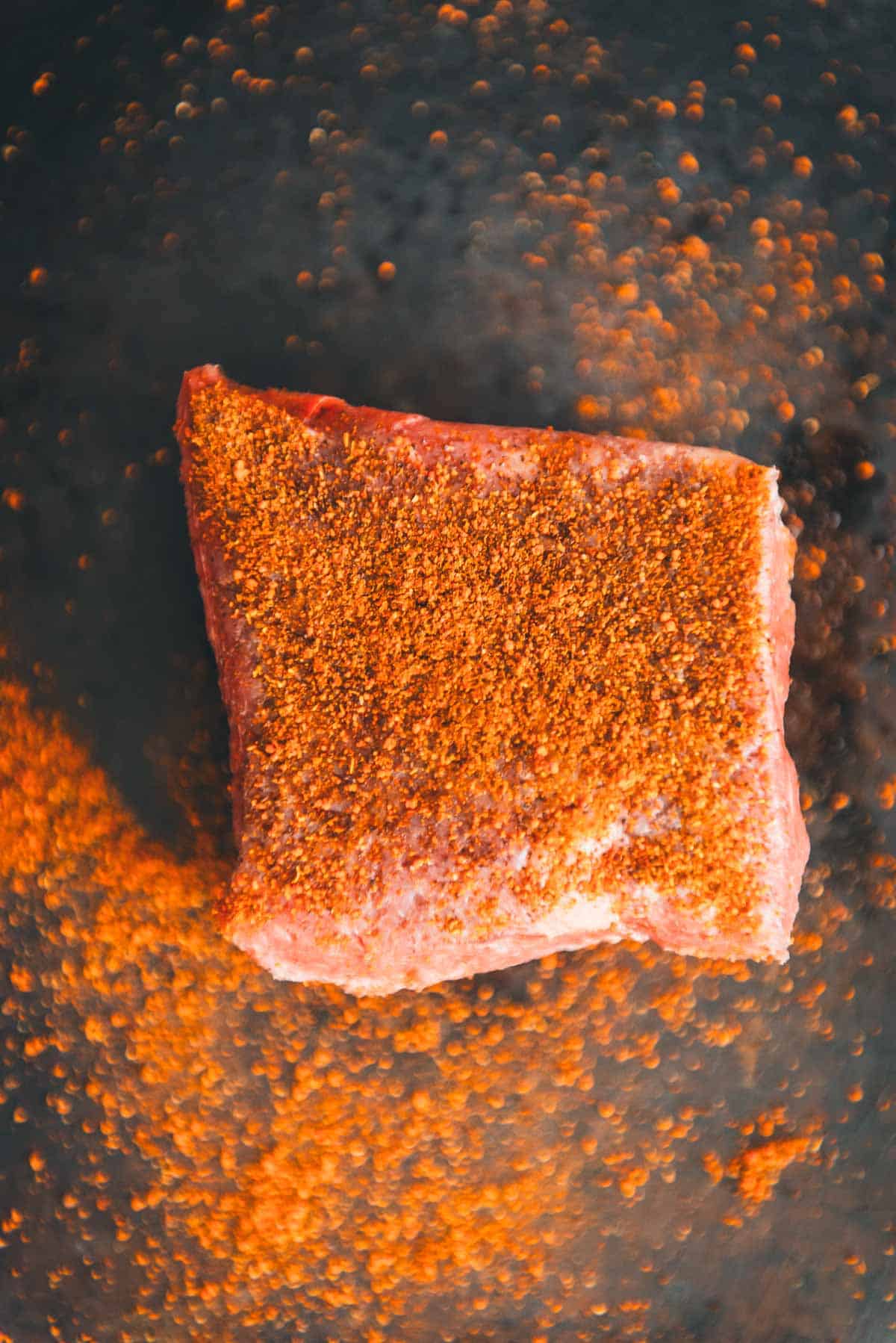 A denver steak coated in spices.