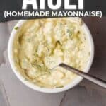 Pinterest image showing a bowl of cilantro avocado aioli, a homemade mayonnaise, garnished with herbs. text overlay includes a recipe link and suggested uses for seafood and tacos.