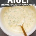 Bowl of homemade herb aioli with a spoon, labeled "how to make herb aioli (homemade mayonnaise)," suggesting suitability for seafood, chicken, and veggies; pinterest image.