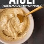 Pinterest graphic showing homemade umami aioli in a bowl with a wooden spoon, titled "how to make aioli (homemade mayonnaise)" with a website link and suggested food pairings.