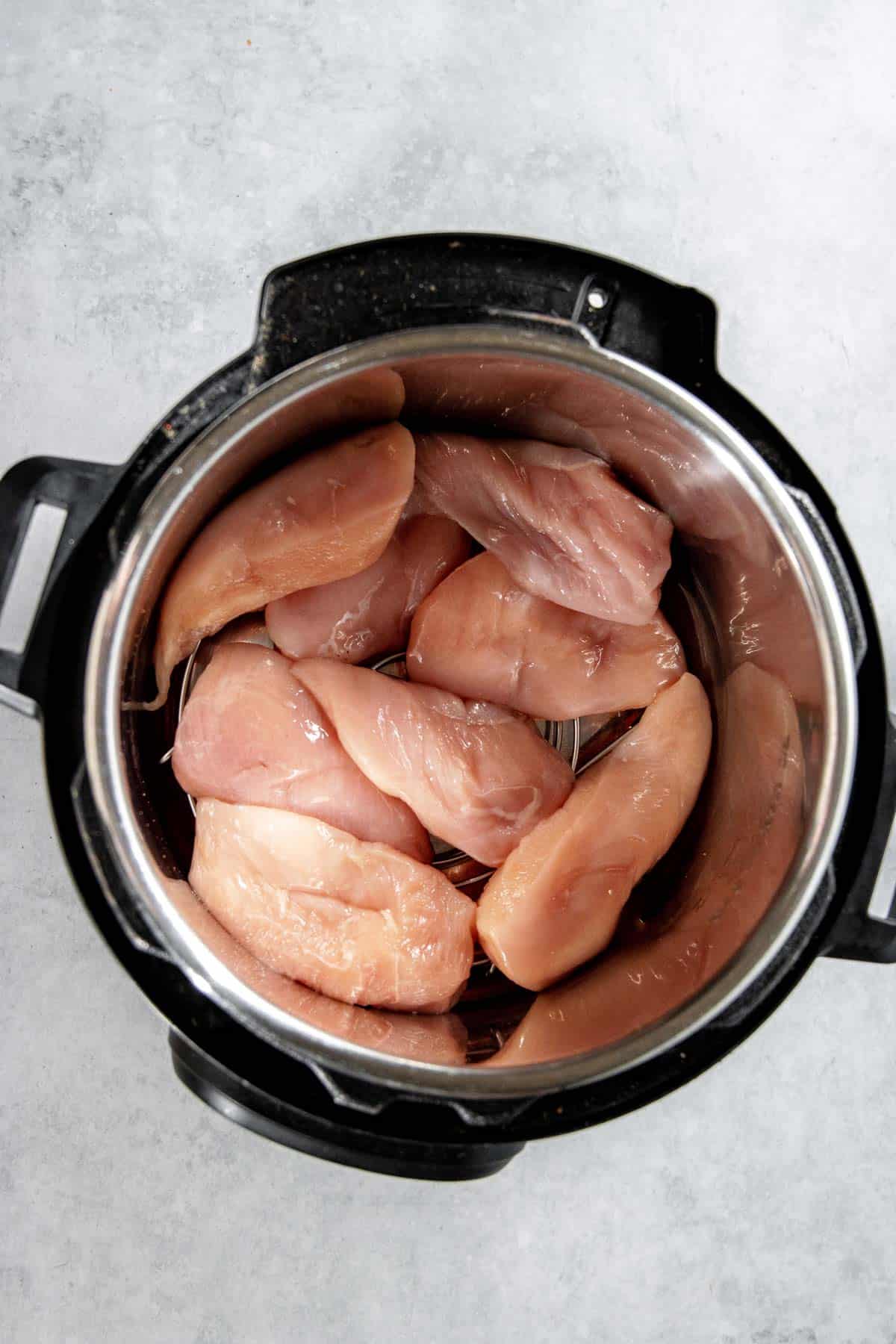 Raw chicken breasts placed inside an Instant Pot, viewed from above.