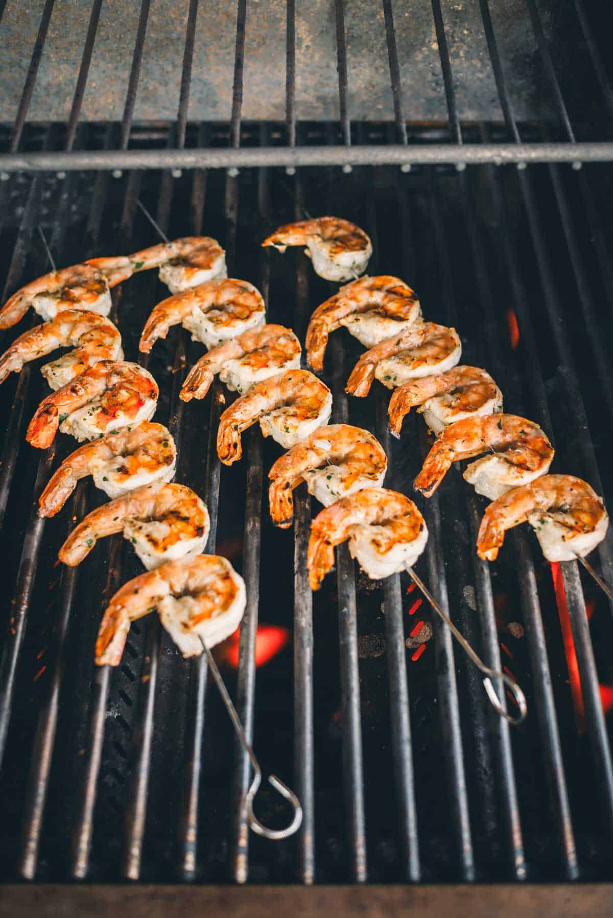 Shrimp is being grilled on skewers over an open flame.