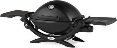 A black Weber tabletop propane grill with side shelves and a dome-shaped lid, perfect for your camp kitchen.