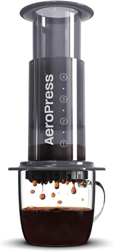 Image of an AeroPress coffee maker placed over a glass mug as coffee drips into the mug, perfect for your camp kitchen setup.