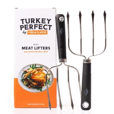 Two meat lifters with black handles and four-pronged stainless steel ends are displayed next to a "Turkey Perfect by Fire & Flavor" box. The box shows an image of a roasted turkey on a plate.