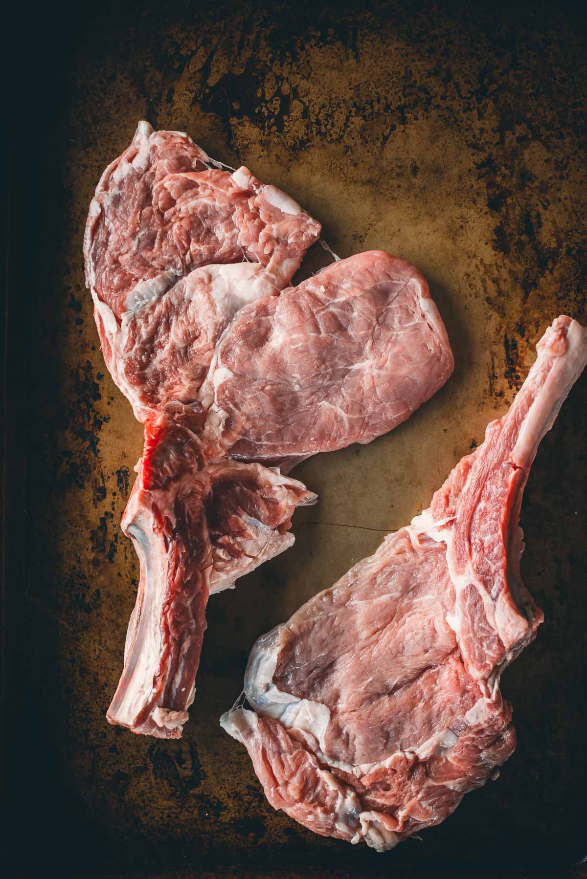 Bone in veal chops with the meat pounded thin to show what it will look like while still on the bone. 