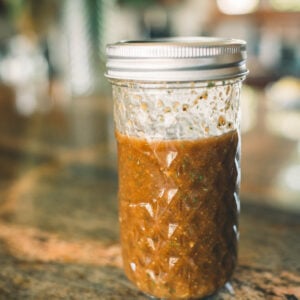 A glass jar filled with balsamic elk steak marinade sits on a countertop.