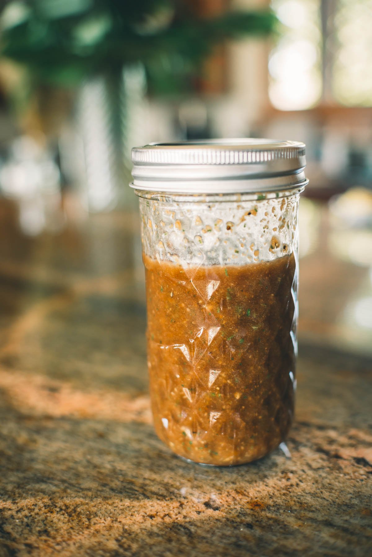 A glass jar filled with balsamic elk steak marinade sits on a countertop.