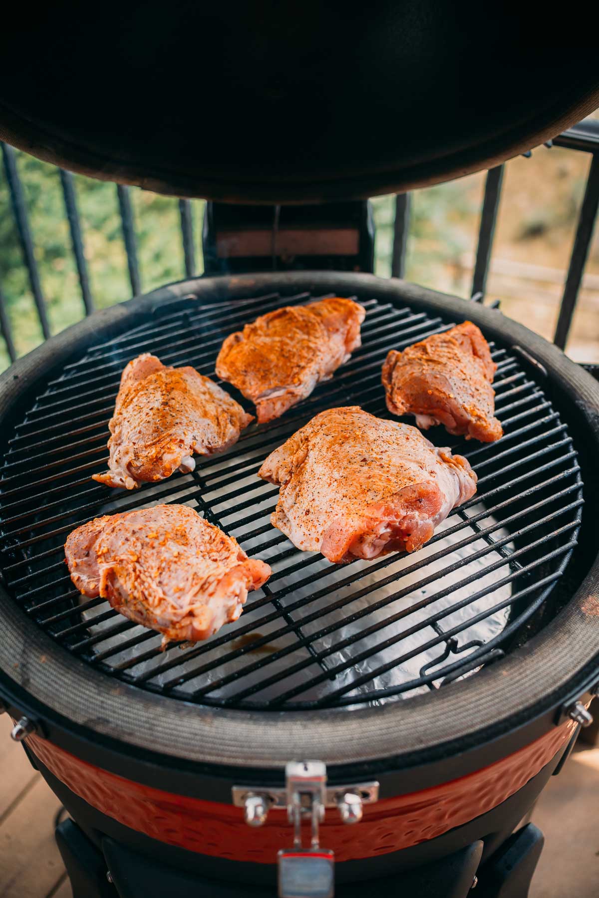 Seasoned raw turkey thighs on a black grill, ready for cooking.