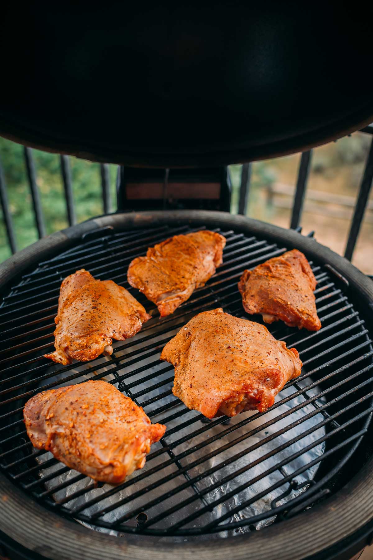 Seasoned turkey thighs cooking on an outdoor grill.