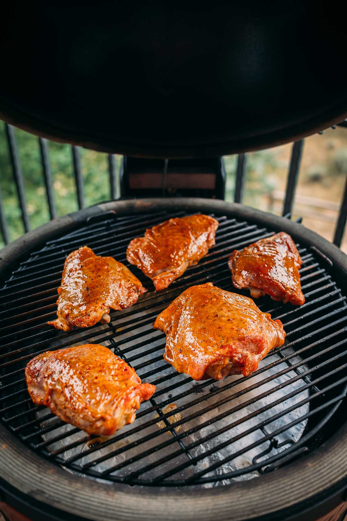 Turkey thighs coated in maple glaze are being grilled on a round barbecue grill.