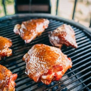 Grilled turkey pieces coated with sauce cook on a barbecue grill.