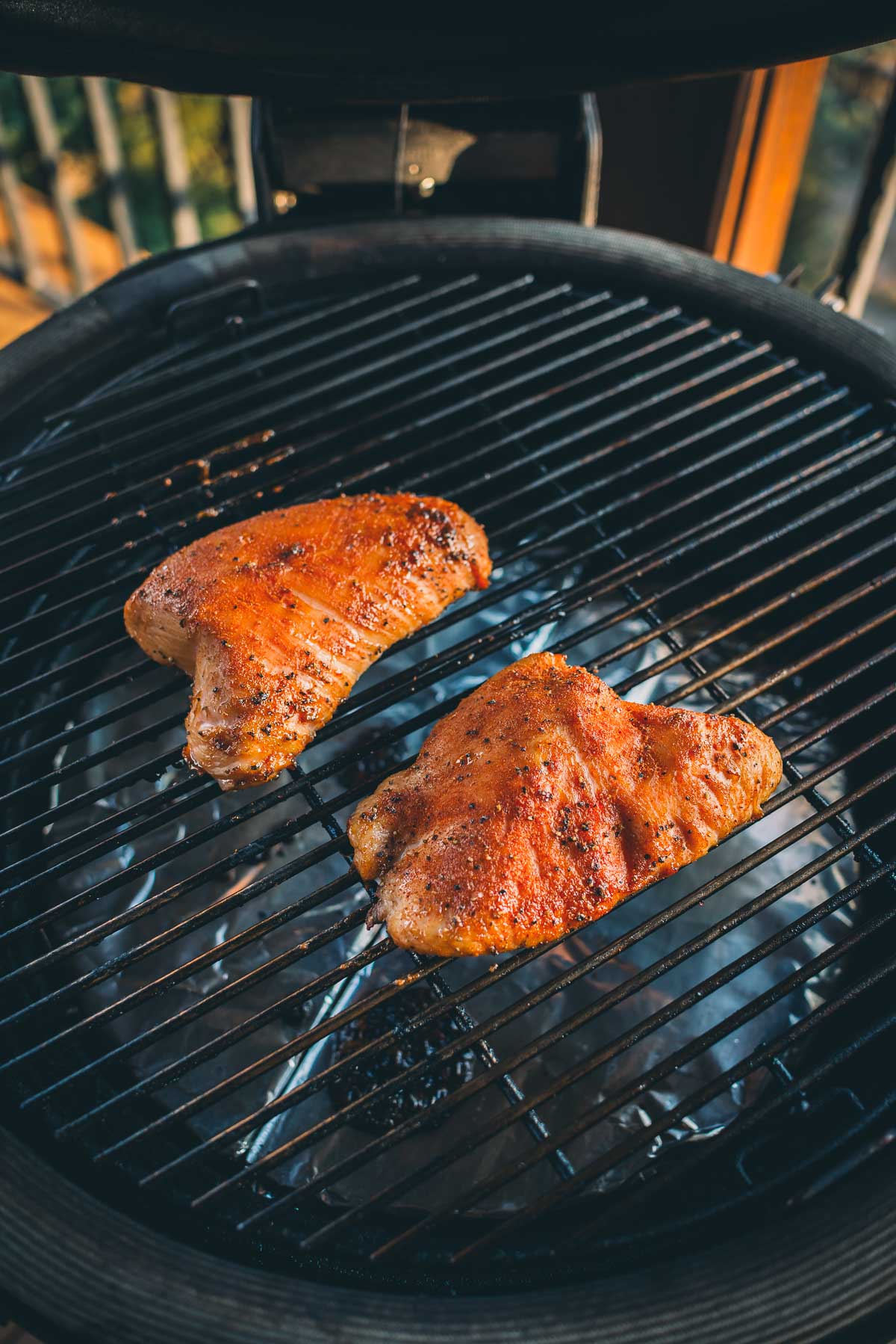 Two seasoned turkey tenderloins smoking on a barbecue.