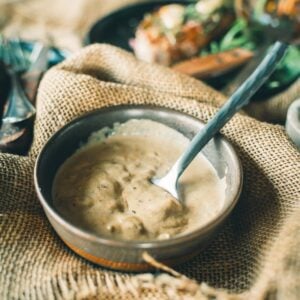 A bowl of mustard cream sauce with a spoon, set on a burlap cloth.