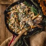 Skillet with ground turkey stroganoff in pasta topped with a creamy sauce and herbs, garnished with grilled onions.