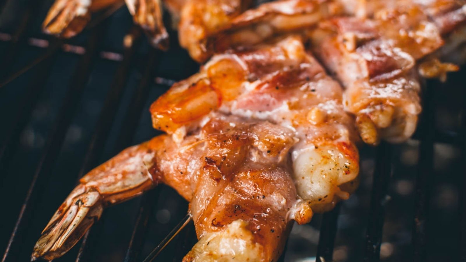 Shrimp wrapped in bacon, grilling on a barbecue.