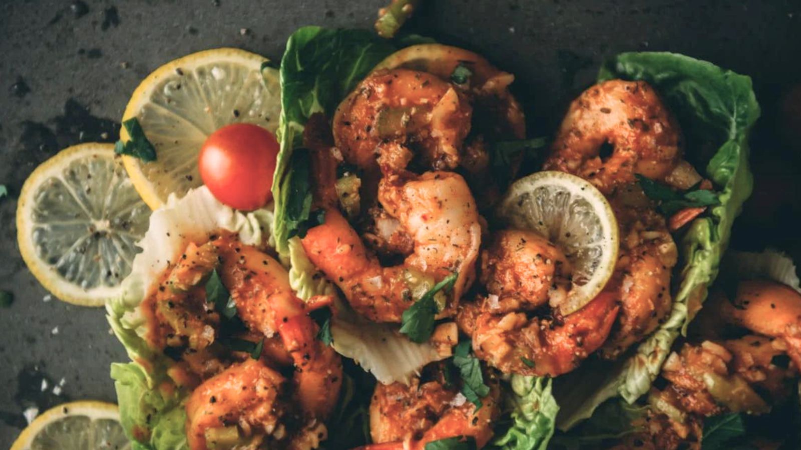 Shrimp on lettuce leaves garnished with lemon slices, cherry tomato, and herbs make delightful Christmas appetizers.