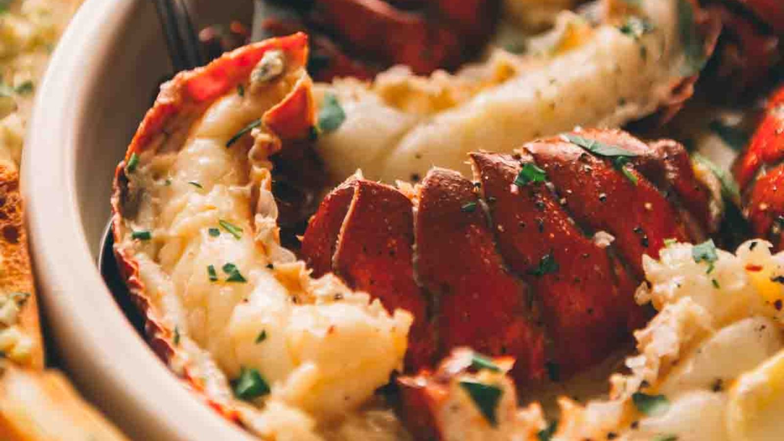 Close-up of a dish featuring lobster meat garnished with chopped herbs, served in a bowl.