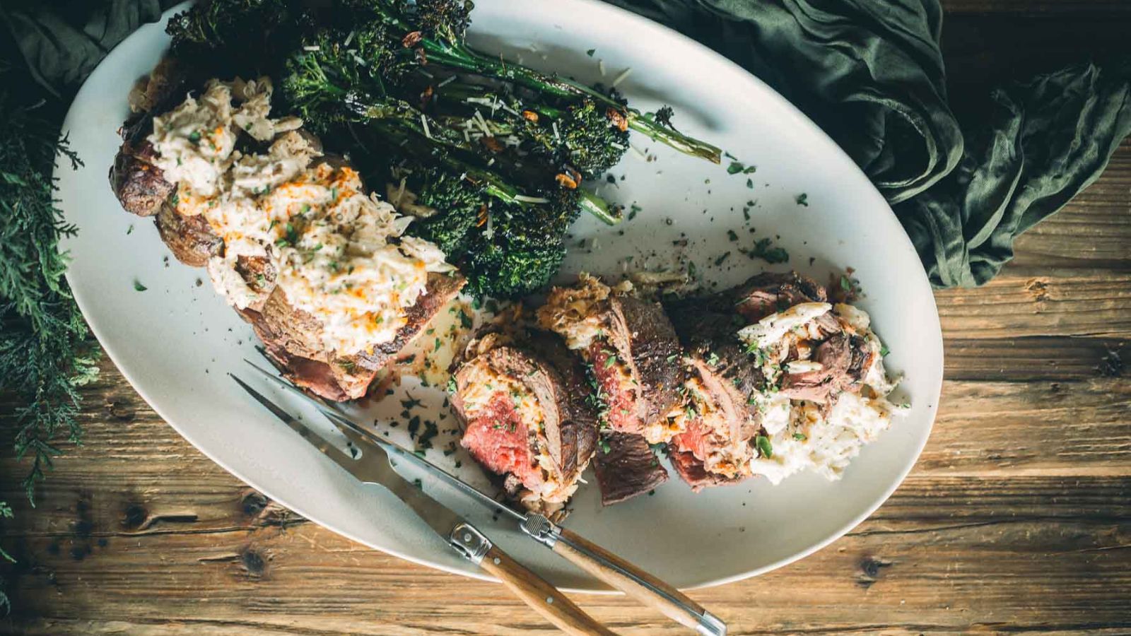 A platter with sliced steak topped with one of the best sauces for beef tenderloin, served alongside roasted broccoli and herbs. Forks placed beside the dish.