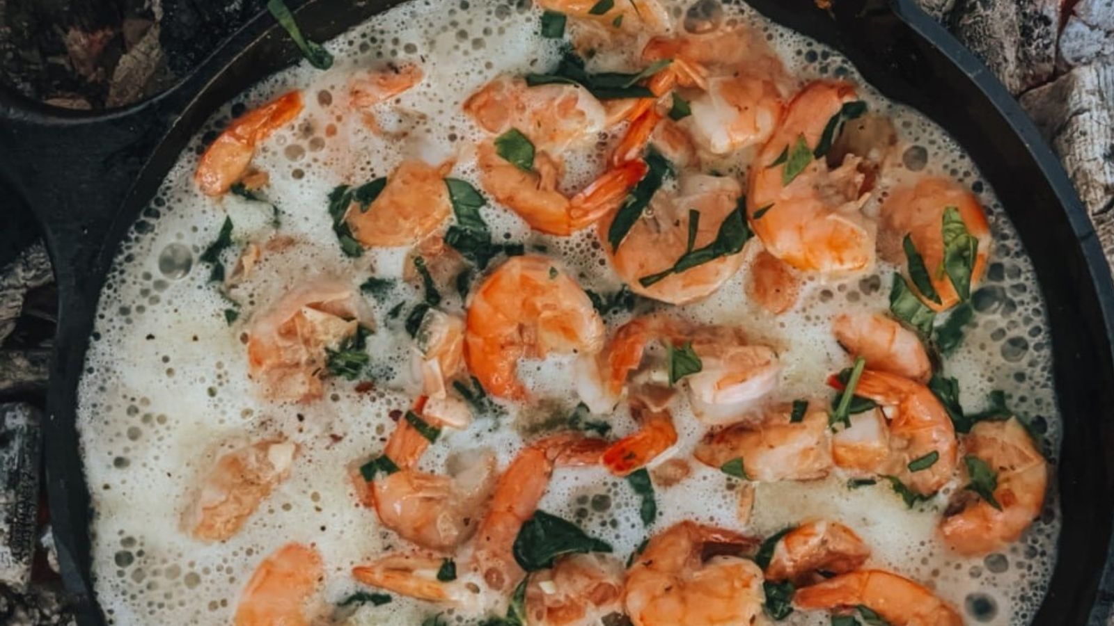 Cooking shrimp with herbs in a bubbling sauce in a black skillet makes for delightful Christmas appetizers.