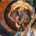 Plate of sous vide short ribs with mashed potatoes and vegetables, garnished with herbs, on a rustic wooden table.