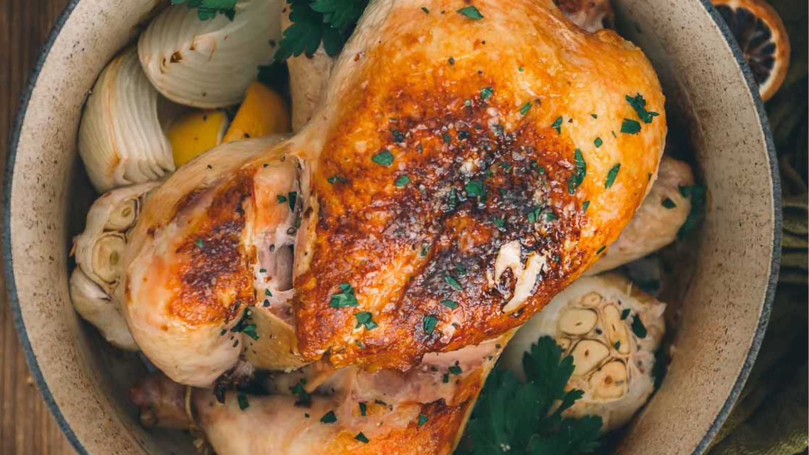 Roasted chicken with herbs, garlic, lemon, and parsley in a bowl.