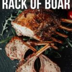 Roasted rack of boar garnished with greens and tomatoes, on a dark surface. Text reads: "How to Make a Roasted Rack of Boar.