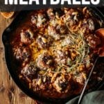 Skillet with French onion meatballs topped with melted cheese and herbs.