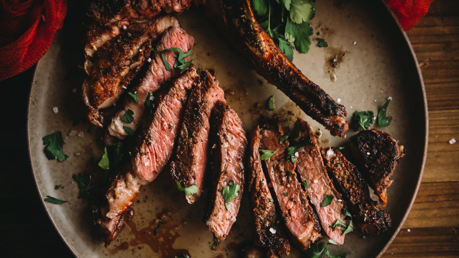 Sliced medium-rare steak with herbs served on a round plate, perfect for romantic Valentine's Day surf and turf recipes.