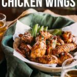 Plate of lemon pepper chicken wings on a napkin with celery sticks and glasses of amber liquid; text reads "How to Make Lemon Pepper Chicken Wings.