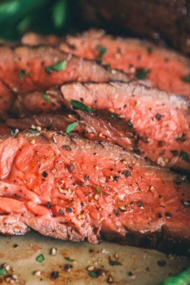 Slices of medium-rare steak garnished with herbs are artfully paired with roasted carrots and green beans on a plate, offering an elegant twist on classic surf and turf recipes for Valentine's Day.