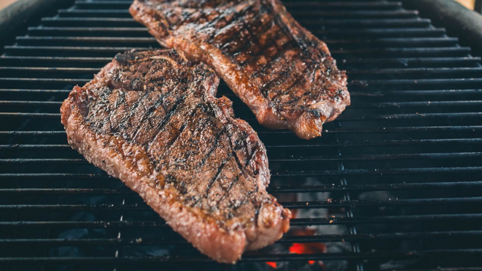 Two steaks sizzling on the grill showcase perfect char marks, creating a tantalizing beginning to your surf and turf Valentine's Day feast.