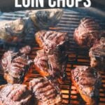 Grilled lamb loin chops cooking on an outdoor grill with smoke rising, accompanied by grilled onions.