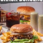 A cheeseburger with lettuce, onions, and fries is served on a plate, with drinks and another burger in the background. Text reads "How to make smashed crack burgers.