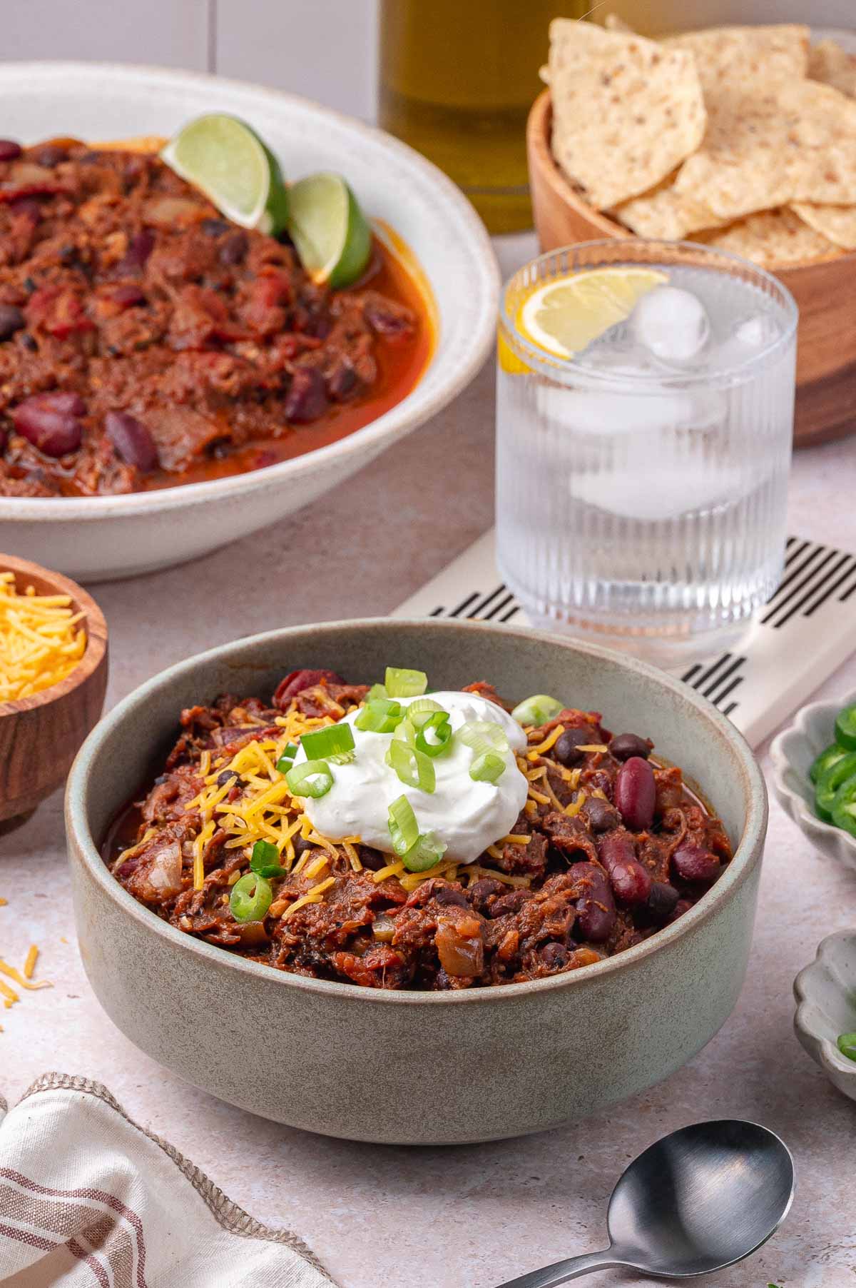 A bowl of pulled pork chili with sour cream and cheese.