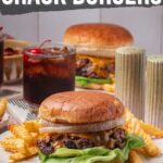 A plate with a smashed burger topped with lettuce and onion, served with crinkle fries and a drink; text above reads "How to Make Smashed Crack Burgers.
