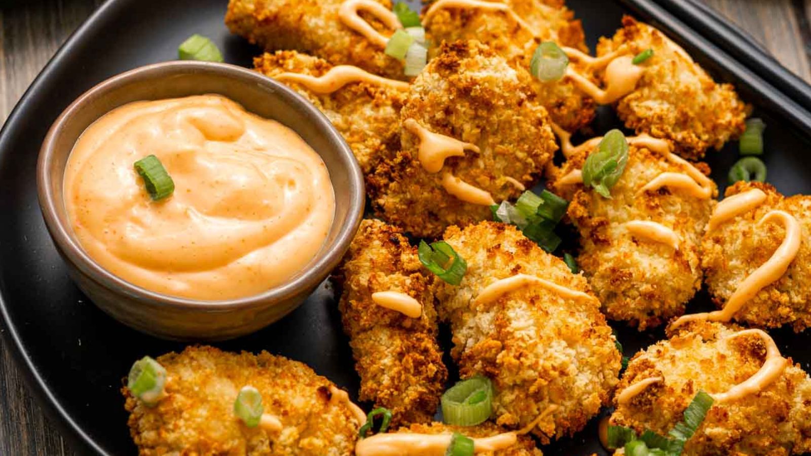 Small bowl of bang bang sauce with a glossy spicy-sweet finish and sesame seeds.