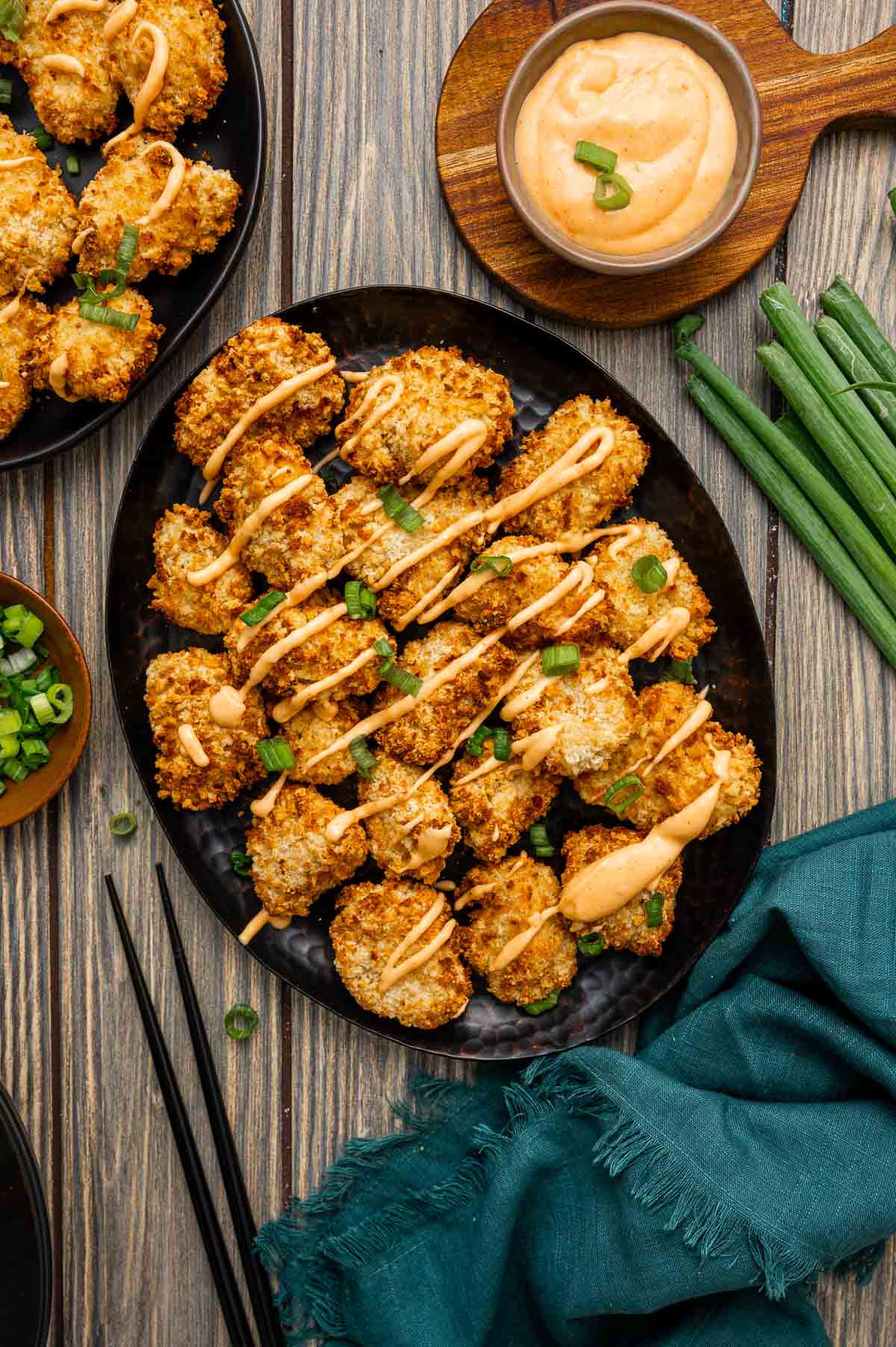 Bowl of chicken bites tossed in creamy Bang Bang sauce and garnished with green onions.