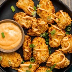 Overhead shot of crispy air fryer chicken bites drizzled with Bang Bang sauce
