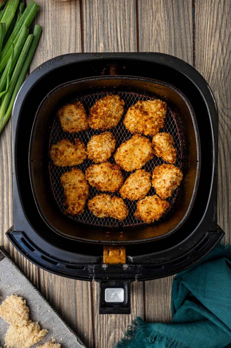 Close-up of golden brown chicken bites in air fryer basket.