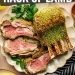 Sliced herb-crusted rack of lamb on a plate with fresh herbs, next to a bowl of creamy polenta and a striped napkin. Text overlay explains how to make the dish.