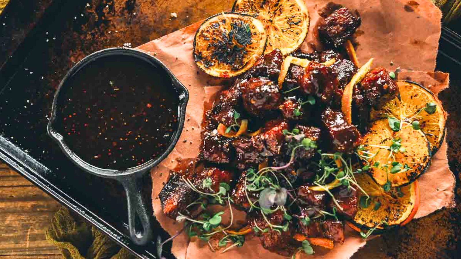 Smoked pork belly burnt ends coated in a glossy maple chipotle bourbon glaze on a tray.