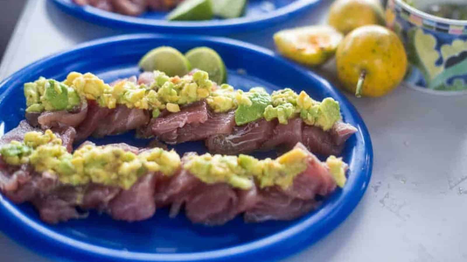Tuna carpaccio topped with avocado and bright passion fruit.